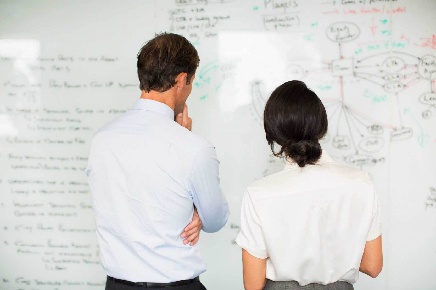 business consultant and client looking at whiteboard together